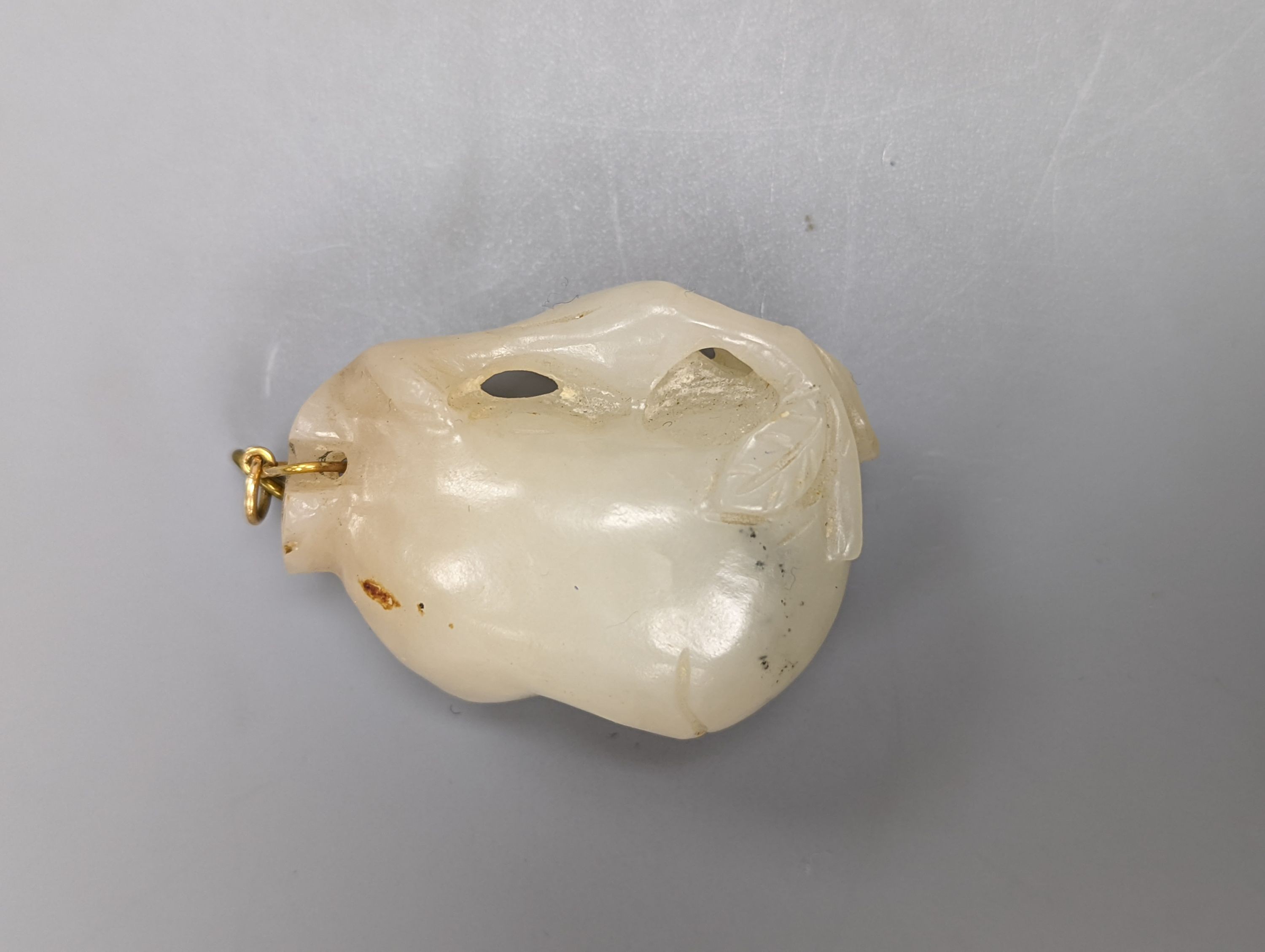 A Chinese whiteish grey jade carving of a peach branch sprig, 19th century, 4.2cm